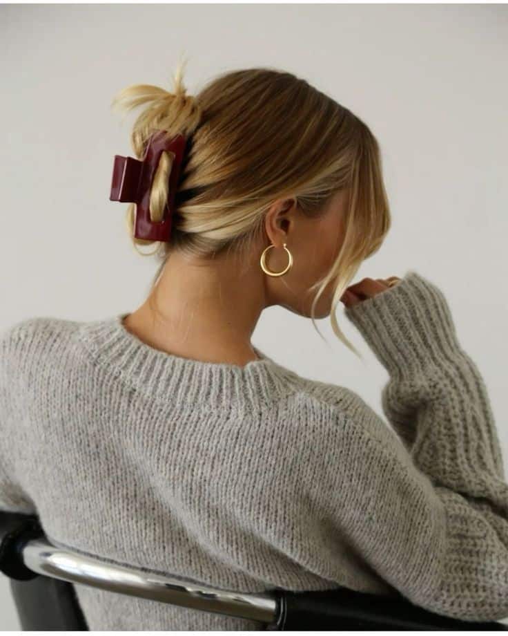 _ 8 Woman with blonde hair in a claw clip, wearing a grey sweater and hoop earrings, sitting on a chair. | Sky Rye Design Woman with blonde hair in a claw clip, wearing a grey sweater and hoop earrings, sitting on a chair.