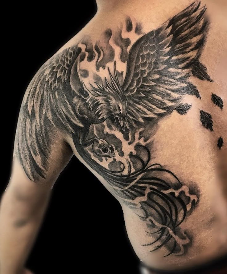 Phoenix tattoo on shoulder and chest, featuring flames and intricate details in black ink.