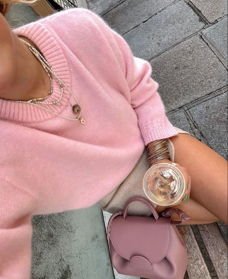 80ee5ffa-2a63-446d-a180-6d141148fe91 Woman in a pink sweater with layers of necklaces, holding iced coffee, next to a stylish pink handbag on a bench. | Sky Rye Design Woman in a pink sweater with layers of necklaces, holding iced coffee, next to a stylish pink handbag on a bench.