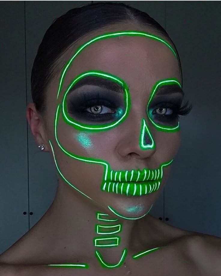 Woman with glowing green neon skeleton face paint and dramatic eye makeup.