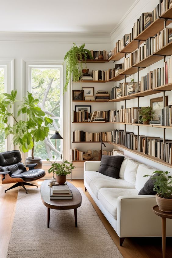 Modern living room with bookshelves, white sofa, large window, indoor plants, and cozy decor.