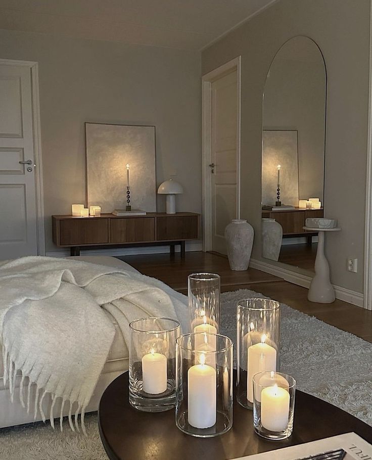 Cozy living room with candles, soft lighting, round mirror, and modern decor for a warm, inviting ambiance.