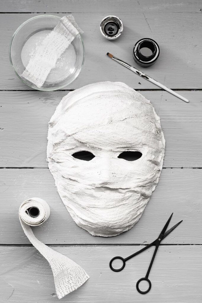 8c3e6208f4b721b20e6bca8eca5fffbf DIY plaster mask creation with bandages, scissors, and paintbrush on a wooden table. | Sky Rye Design DIY plaster mask creation with bandages, scissors, and paintbrush on a wooden table.