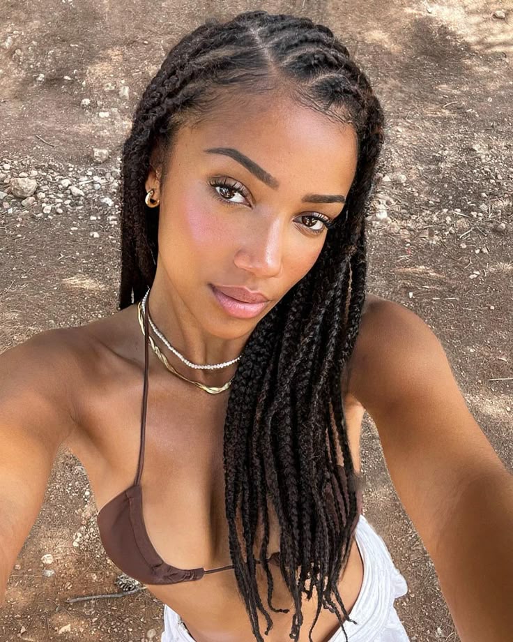 Woman in braided hairstyle takes a selfie in a bikini, showcasing natural beauty and style outdoors.