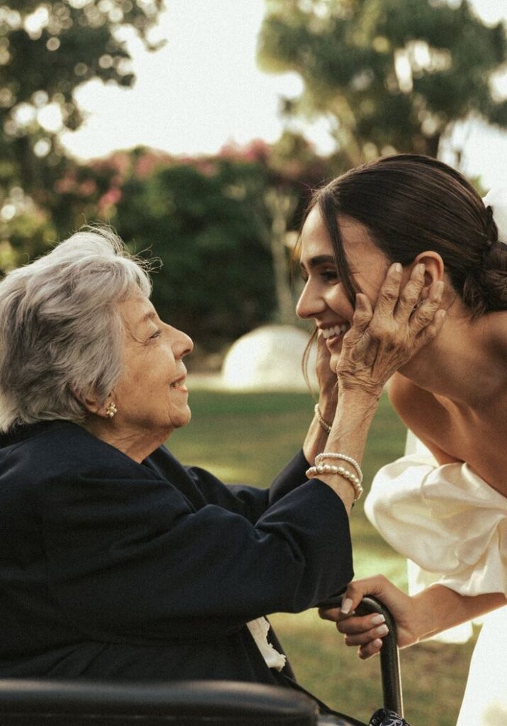 Grandmother and bride sharing a heartfelt moment outdoors, smiling and embracing.