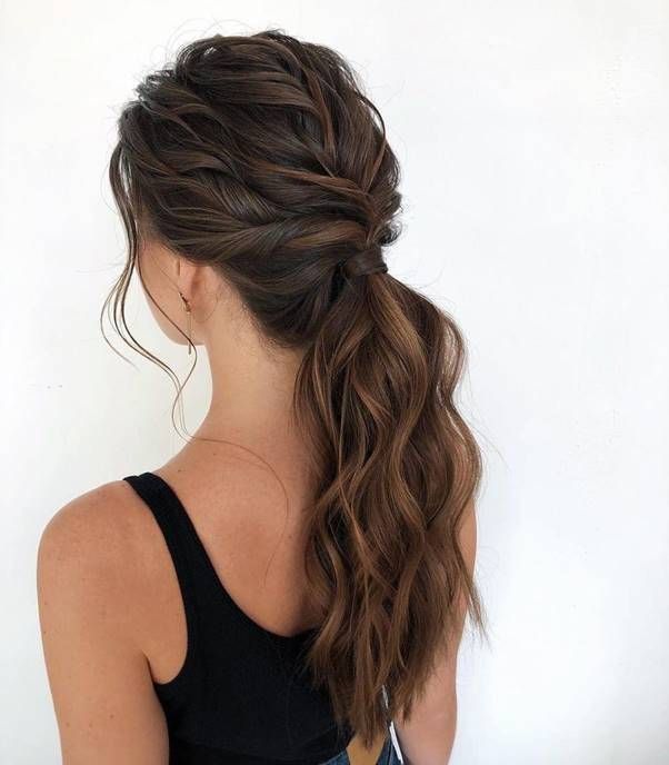Woman with long, wavy brown hair in a braided ponytail, wearing a black top, viewed from the back.