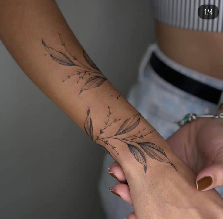 Elegant floral tattoo design on forearm, showcasing intricate leaf patterns and delicate details.