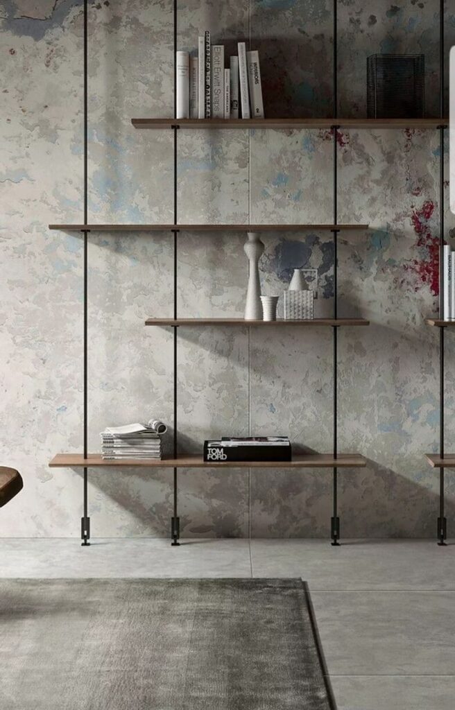 Modern wall-mounted shelves with books and decor against a textured wall, placed above a minimalist carpet.