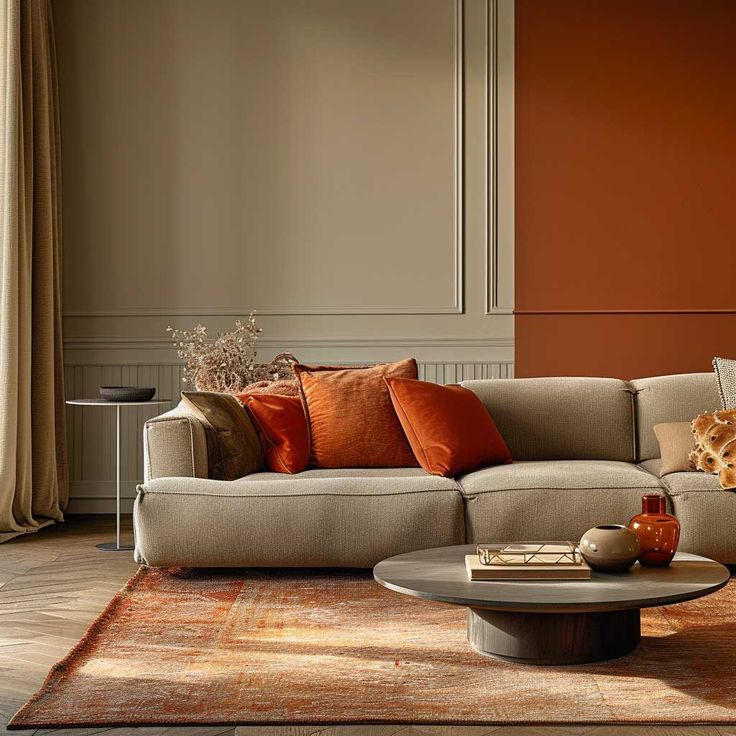 Cozy living room with beige sofa, orange pillows, round table, orange accents, and a textured rug for warm ambiance.