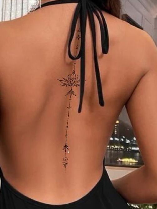 Elegant back tattoo design on woman with open-back black dress.