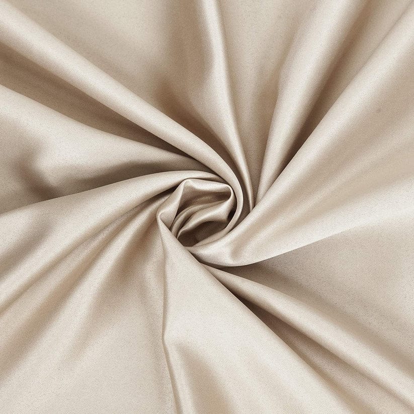 Close-up of beige satin fabric twisted, showcasing its smooth texture and luxurious shine.