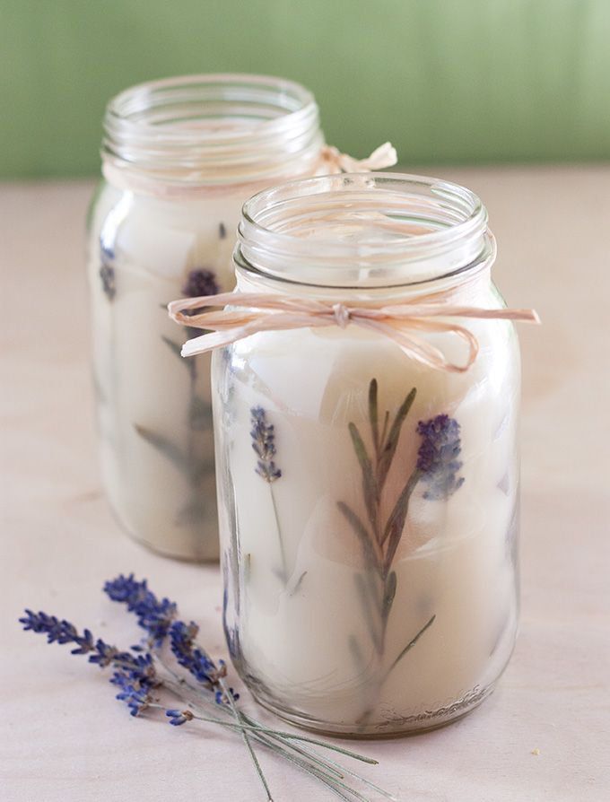 Handmade lavender candles in glass jars with twine bows, displaying a rustic and natural aesthetic.