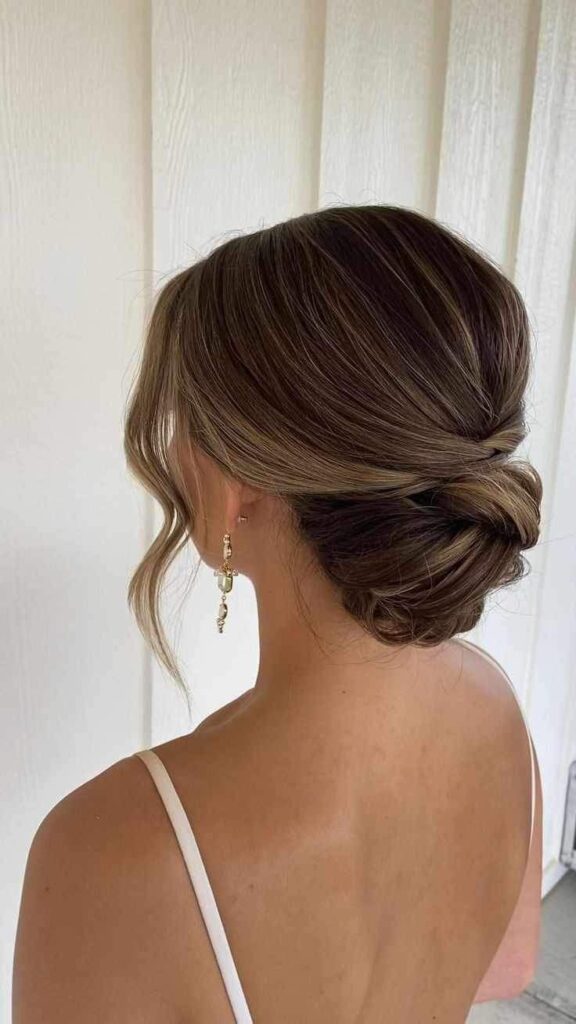 Elegant bridal updo hairstyle with soft curls, showcased from the back, paired with gold earrings.
