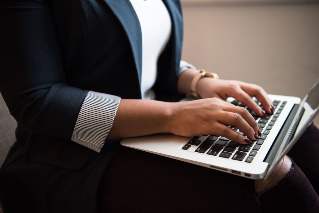 Person in business attire typing on a laptop, focusing on productivity and digital work.