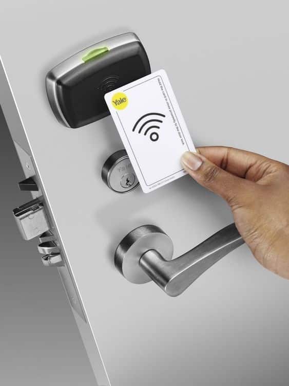 Person using an RFID key card to unlock a secure door with a digital lock system.