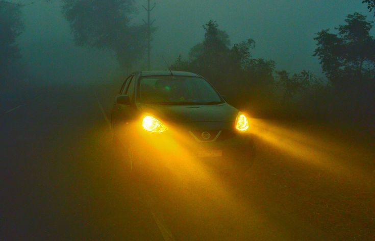 Aprenda a usar farol alto baixo de neblina de milha luzes de rodagem diurna e lanternas Car with headlights on shining through thick fog on a dark, misty road. | Sky Rye Design Car with headlights on shining through thick fog on a dark, misty road.