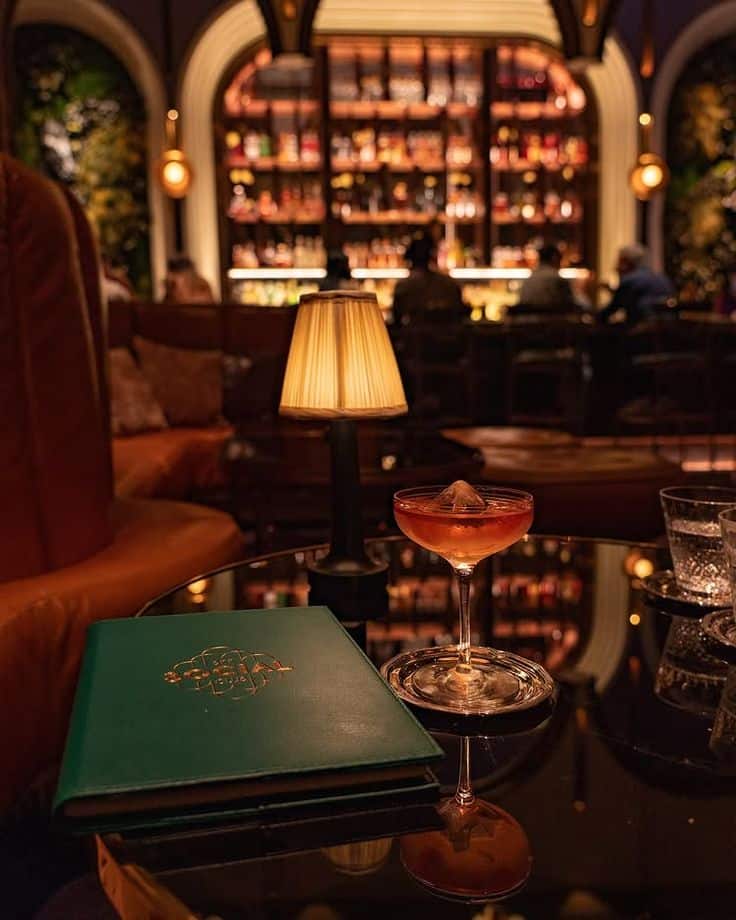 Chic bar setting with a cocktail on a table, ambient lighting, and a stylish bar backdrop. Perfect for a cozy night out.