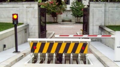 Secure entrance with traffic barrier and security gate in a gated area, red light indicator active.
