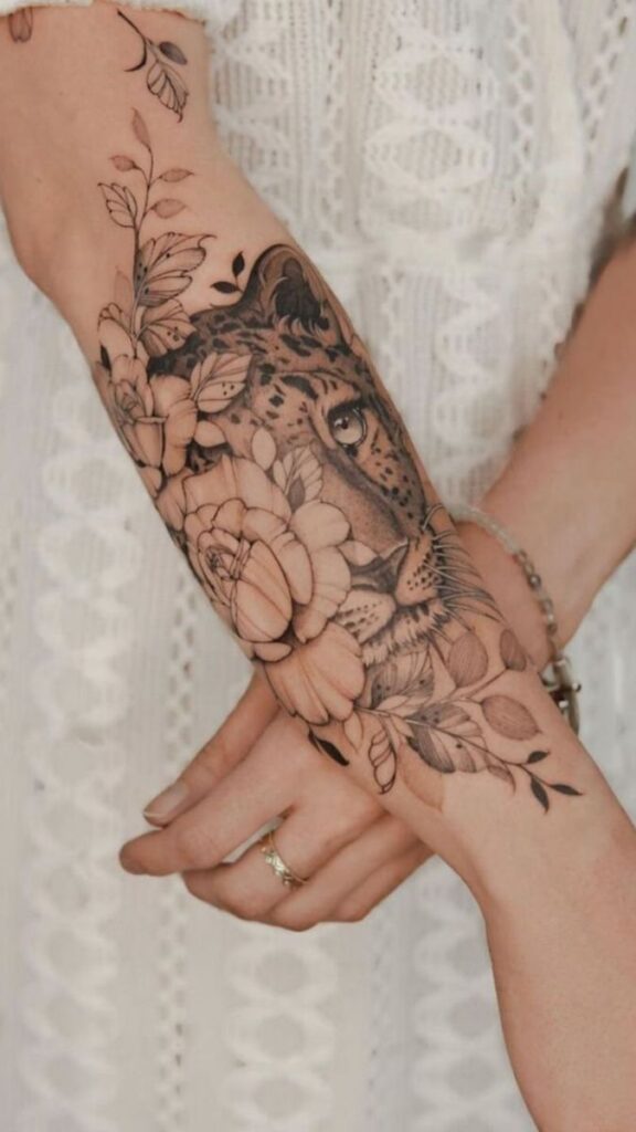 Forearm tattoo with detailed leopard and floral design on a person in a white dress.
