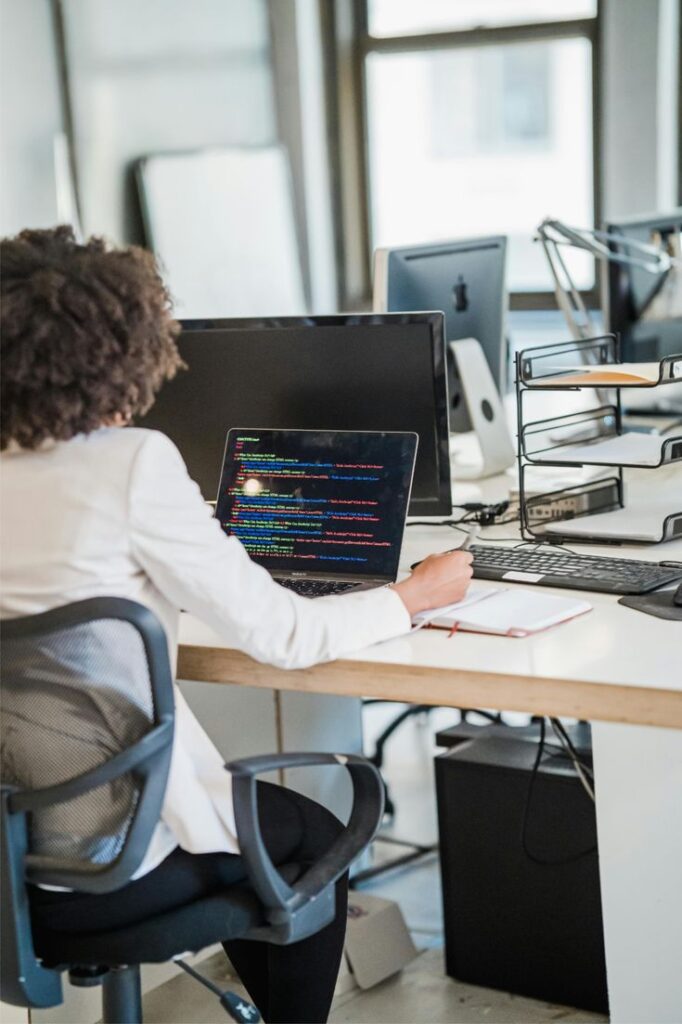 Person coding on a laptop at a modern office desk, focusing on software development.