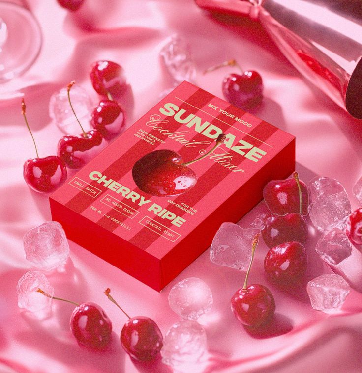 Sundaze cherry ripe cocktail mixer box with fresh cherries and ice, displayed on a pink satin background.