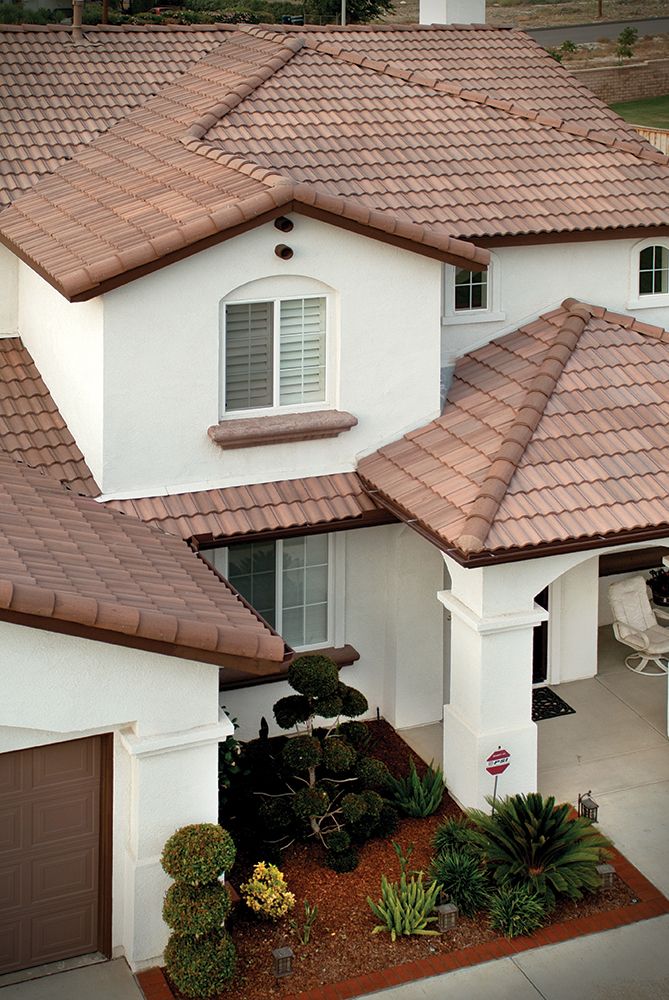 Tan tiled roof house with landscaped front yard and arched windows, viewed from above.