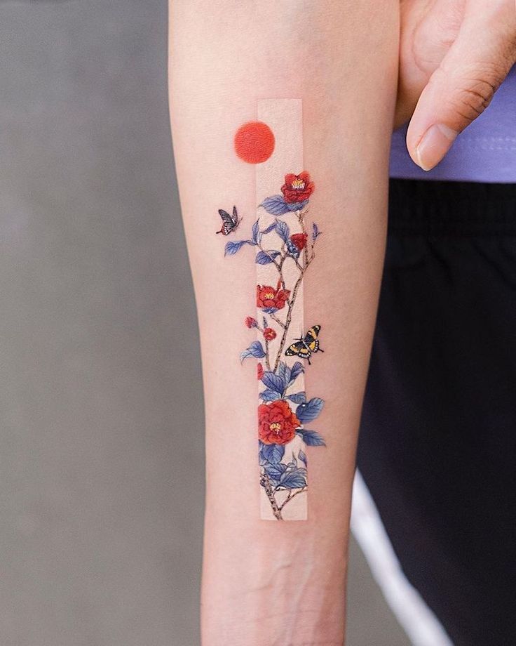 Minimalist forearm tattoo with red flowers, blue leaves, butterflies, and a red sun.