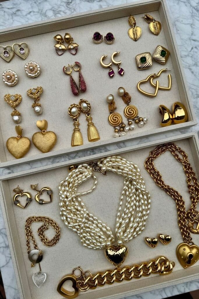 Collection of gold and pearl jewelry including earrings, necklaces, and bracelets displayed on a marble surface.