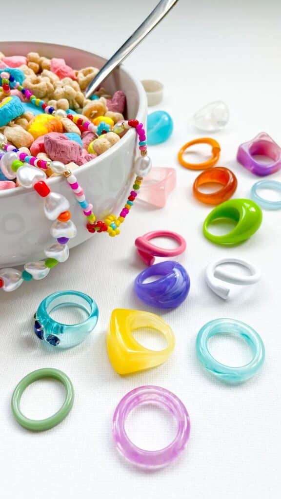 Colorful cereal bowl with beaded bracelet and vibrant rings on white background.
