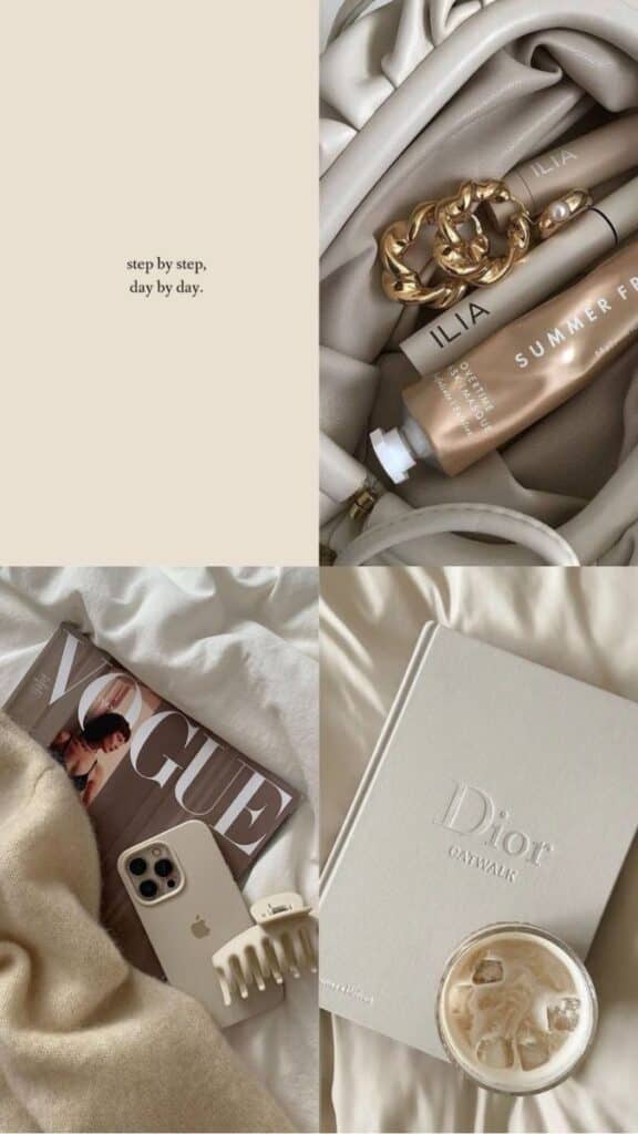 Chic flat lay of luxury beauty products, a Dior book, Vogue magazine, iPhone, hair clip, and iced coffee on beige fabric.