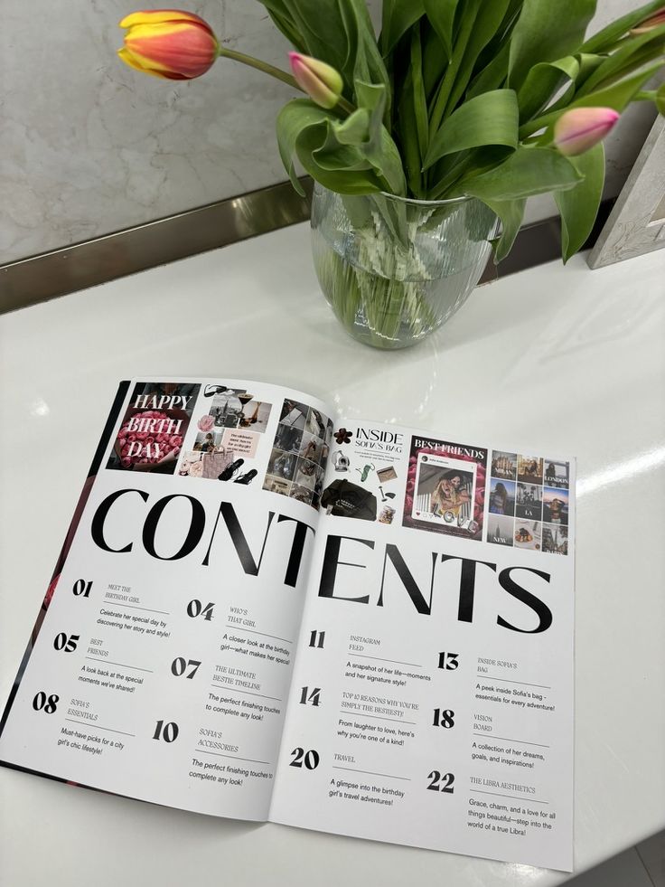 Magazine open to contents page next to a vase of tulips on a marble countertop.