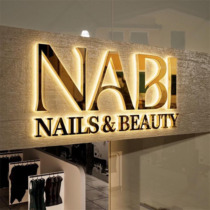 Illuminated Nabi Nails & Beauty sign in a stylish salon interior, showcasing boutique fashion displays.