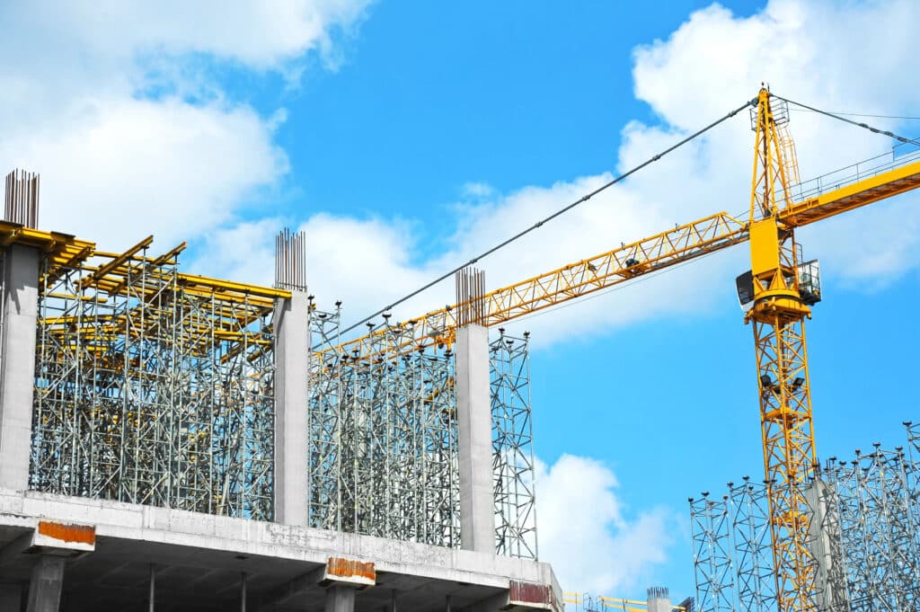 Depositphotos_313329782_XL Construction site with yellow crane and steel framework against blue sky and clouds. | Sky Rye Design Construction site with yellow crane and steel framework against blue sky and clouds.