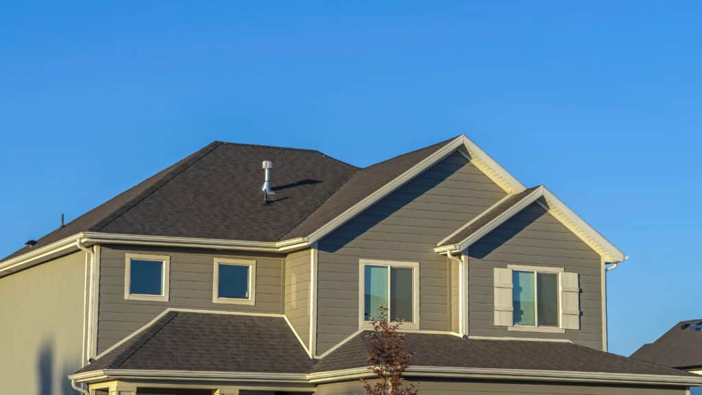 Panorama frame Home exterior with view of the upper storey agaist clear blue sky background Modern suburban house with gray siding and gable roof against a clear blue sky. | Sky Rye Design Modern suburban house with gray siding and gable roof against a clear blue sky.