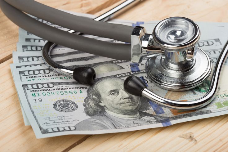 Stethoscope on hundred dollar bills, symbolizing the cost of healthcare and financial implications.