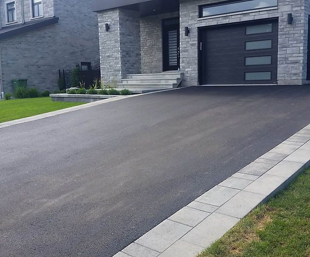 Modern home with smooth asphalt driveway and stone entrance steps.