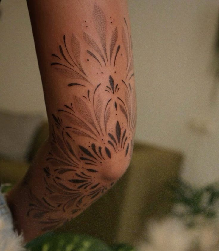 Floral arm tattoo design with black ink patterns on skin, showcasing intricate art and style.