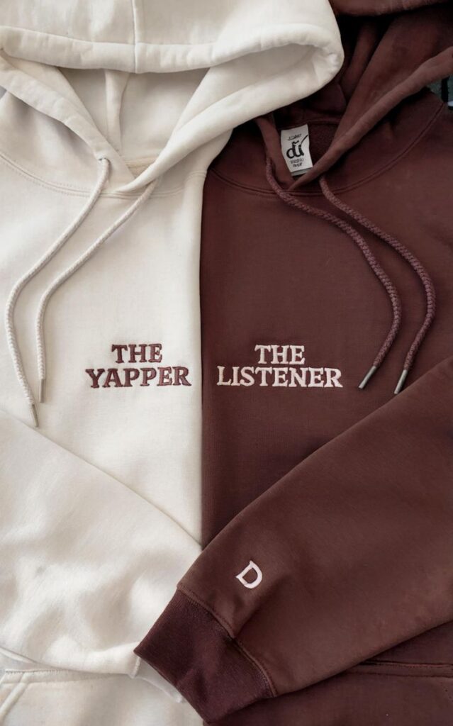 Two hoodies: cream The Yapper and maroon The Listener with drawstrings, laid side by side.