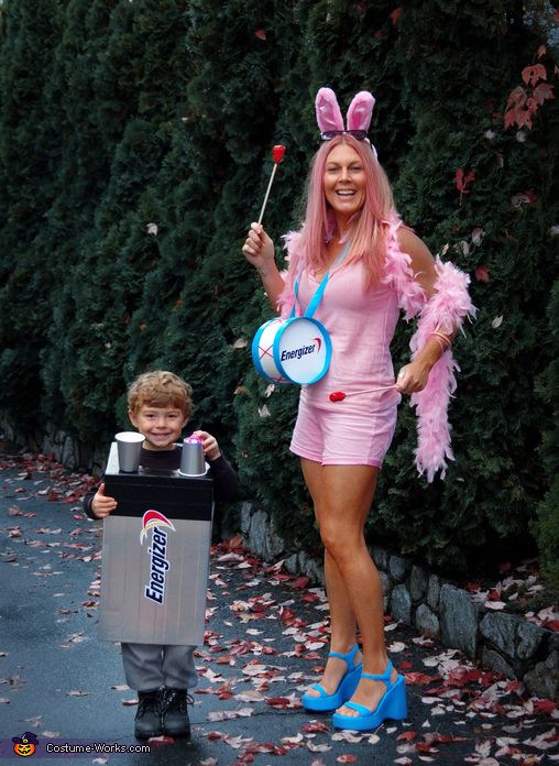 Woman and child in Energizer-themed costumes, dressed as a bunny with drum and a battery, standing outside on a sidewalk.