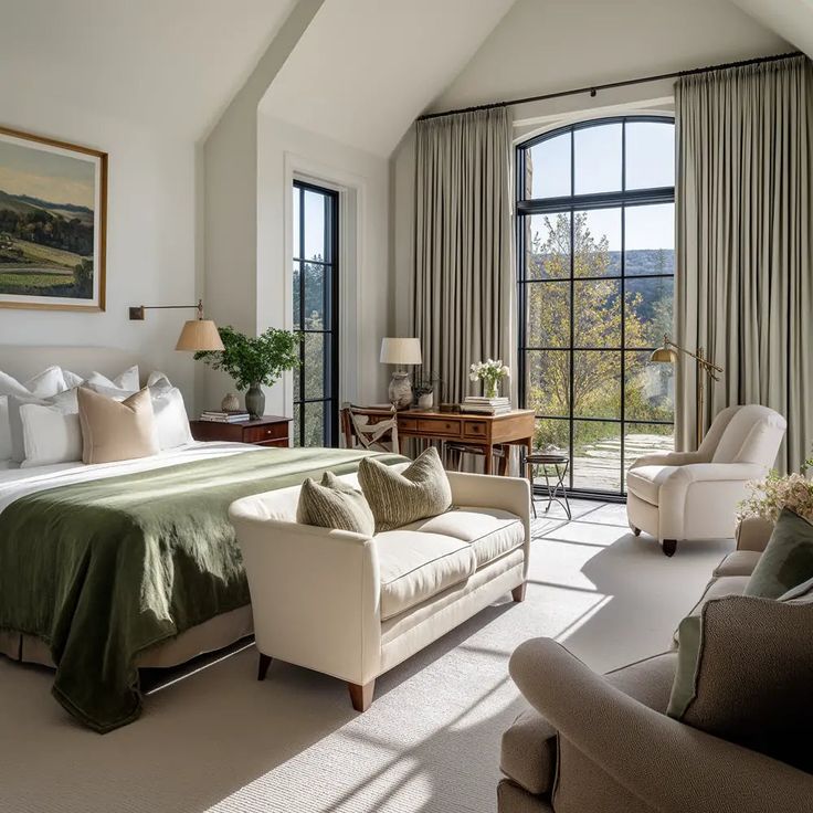Bright, elegant bedroom with green accents, large windows, cozy seating, and natural light streaming in.