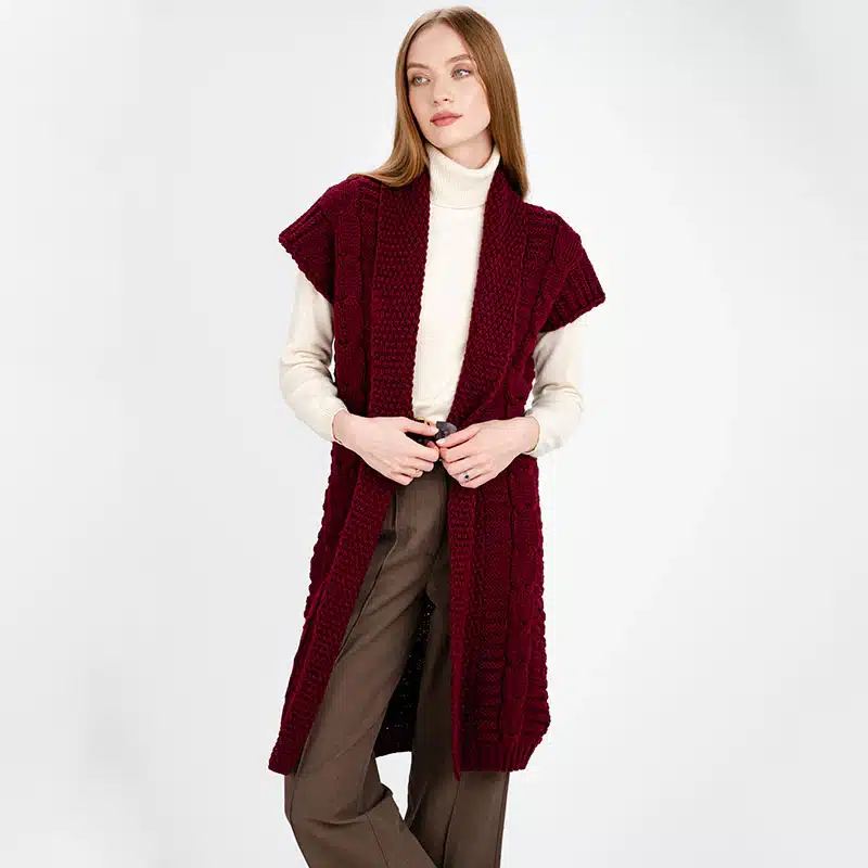 FL177-608-LadiesLong-Irish-Sleeveless-Wool-Cardigan-TaraIrishClothingcom_5_1024x10242x Woman in a burgundy knit vest, cream turtleneck, and brown pants, posing against a plain background. | Sky Rye Design Woman in a burgundy knit vest, cream turtleneck, and brown pants, posing against a plain background.