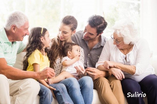 A multi-generational family smiling and sitting together on a sofa, showcasing warmth and togetherness.