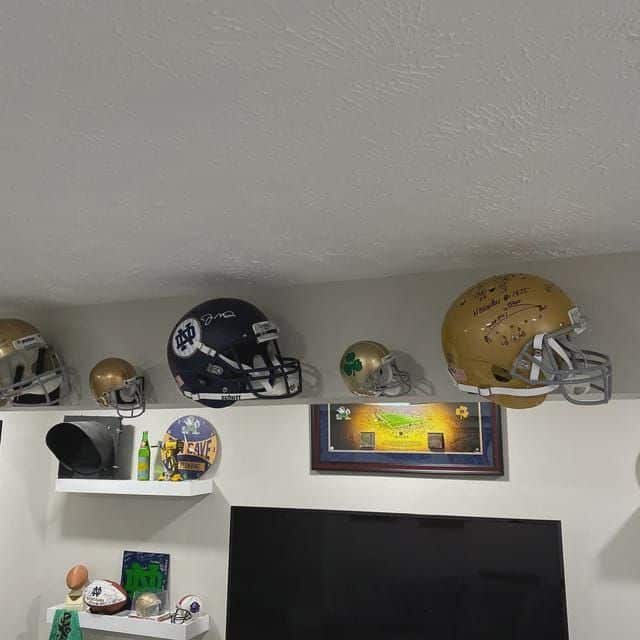 Collection of football helmets and memorabilia displayed on shelves in a fan's room.