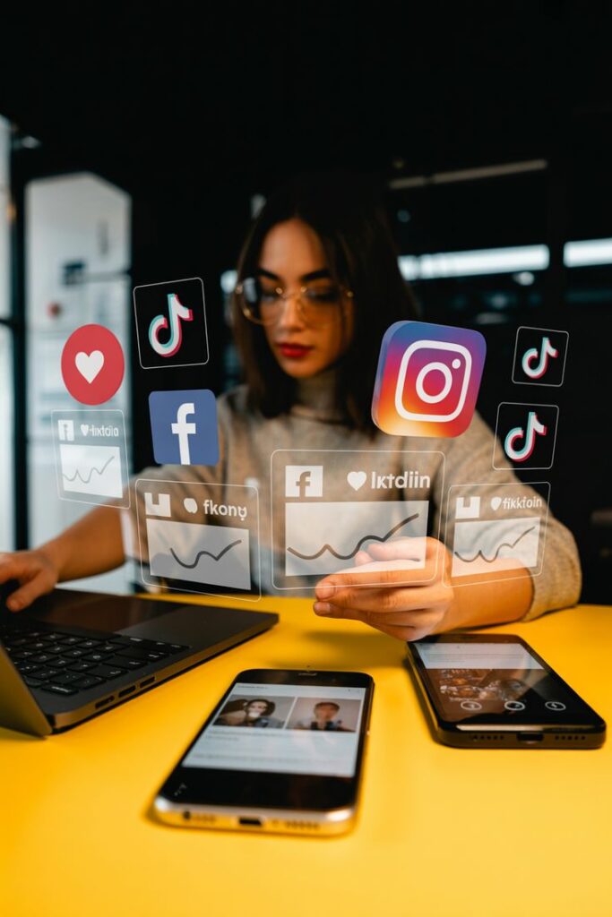 Person using laptop and smartphone with social media icons, analyzing digital trends and engagement metrics.
