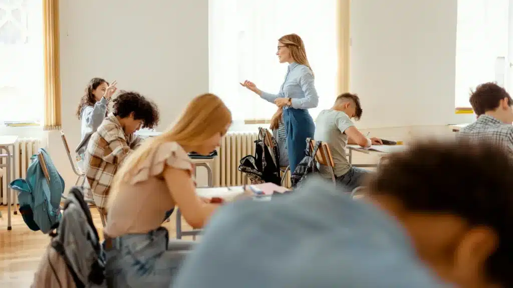 Teacher assisting students during a classroom lesson, with students engaged in various activities.