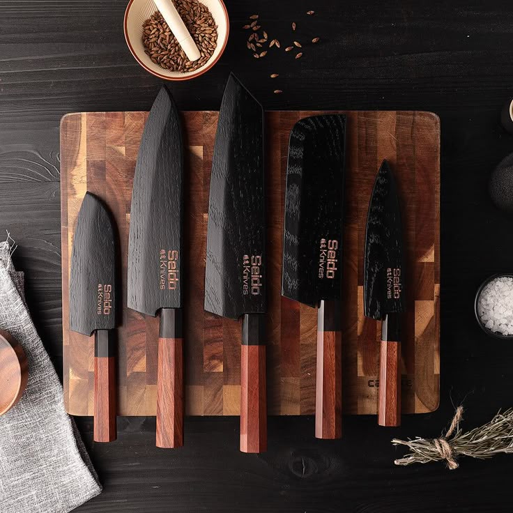 Set of five sleek black-handled knives on a wooden cutting board, perfect for modern kitchen use.