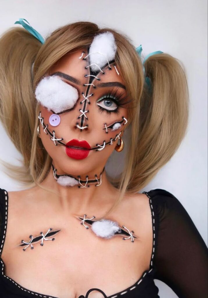 Creative Halloween makeup with stitched doll look and cotton details, worn by person with blonde pigtails.