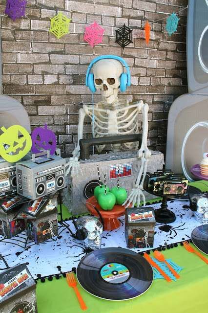 Halloween-themed party table with skeleton DJ, retro decor, vinyl records, and colorful decorations.