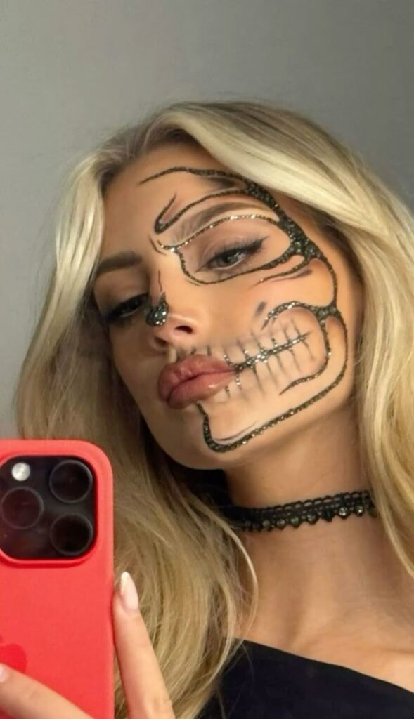 Woman with intricate Halloween face paint resembling a skull takes a selfie, wearing a choker necklace.