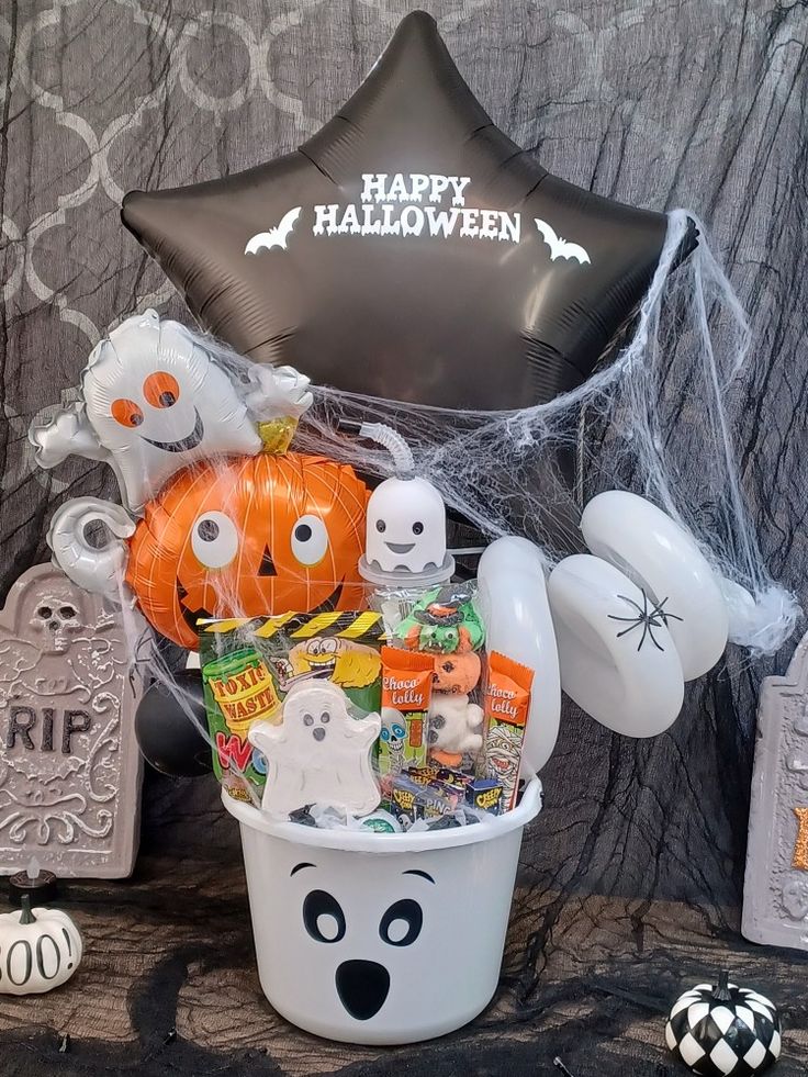 Halloween sweet hamper bucket Halloween gift basket with balloons, candies, and decorations, featuring a ghost-themed container and black star balloon. | Sky Rye Design Halloween gift basket with balloons, candies, and decorations, featuring a ghost-themed container and black star balloon.